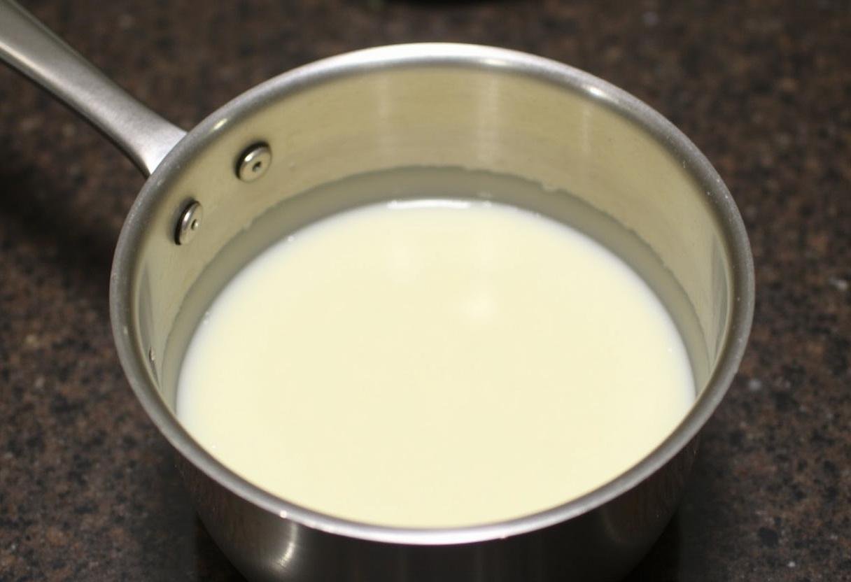 Préparation de la base de crème dessert au chocolat avec du lait, de la crème et du sucre dans une casserole.