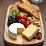 Assiette élégante de Brie de Meaux et Brie de Melun avec fruits frais, noix et pain artisanal.