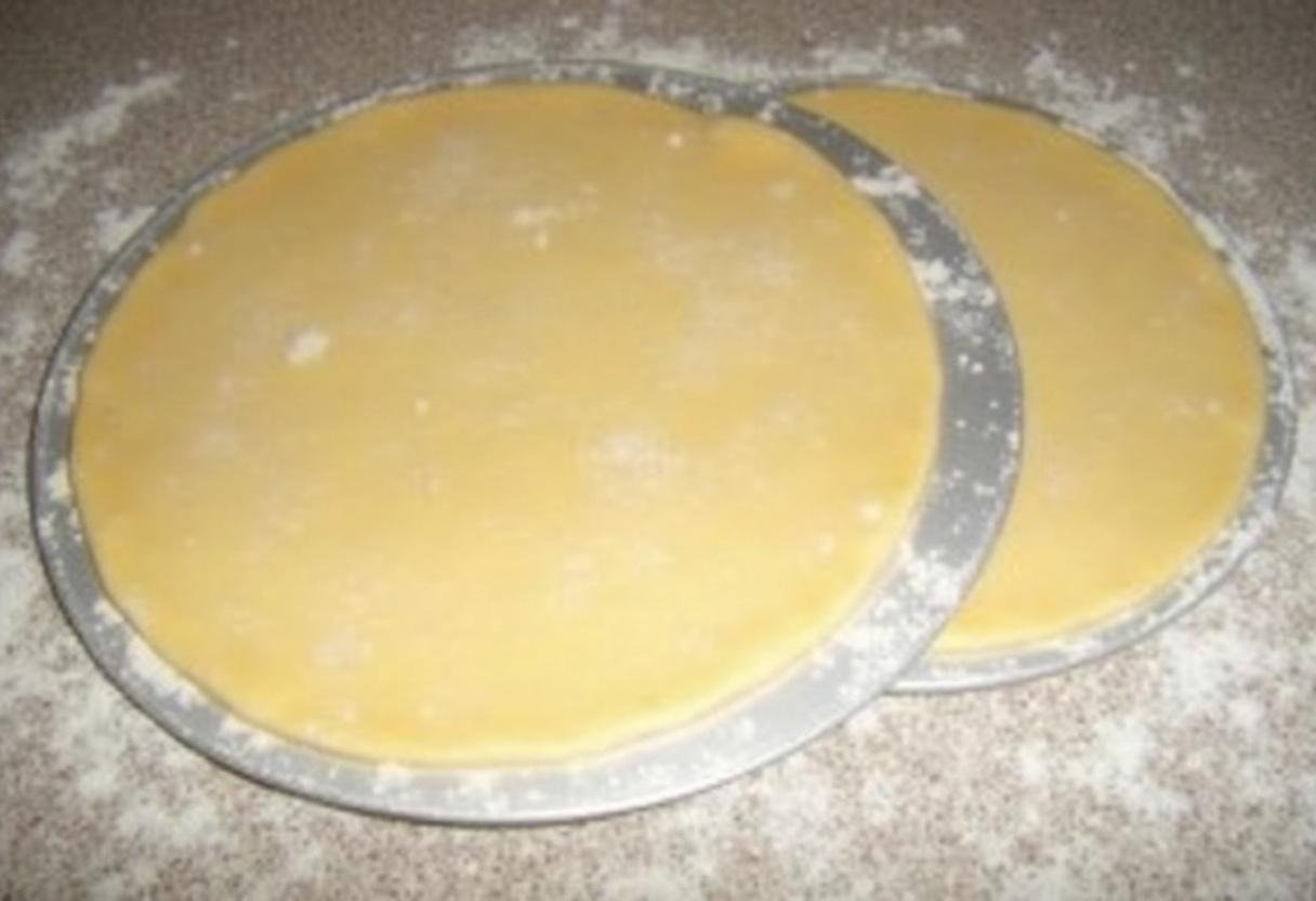 Étaler la pâte pour la galette des rois aux pommes, formant deux cercles avec une pâte légèrement plus grande pour contenir la garniture.