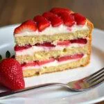 Partie d'un gâteau au mascarpone et fraises, parfaitement présentée sur une assiette avec une fraise fraîche, tout en mettant en valeur une douceur irrésistible.