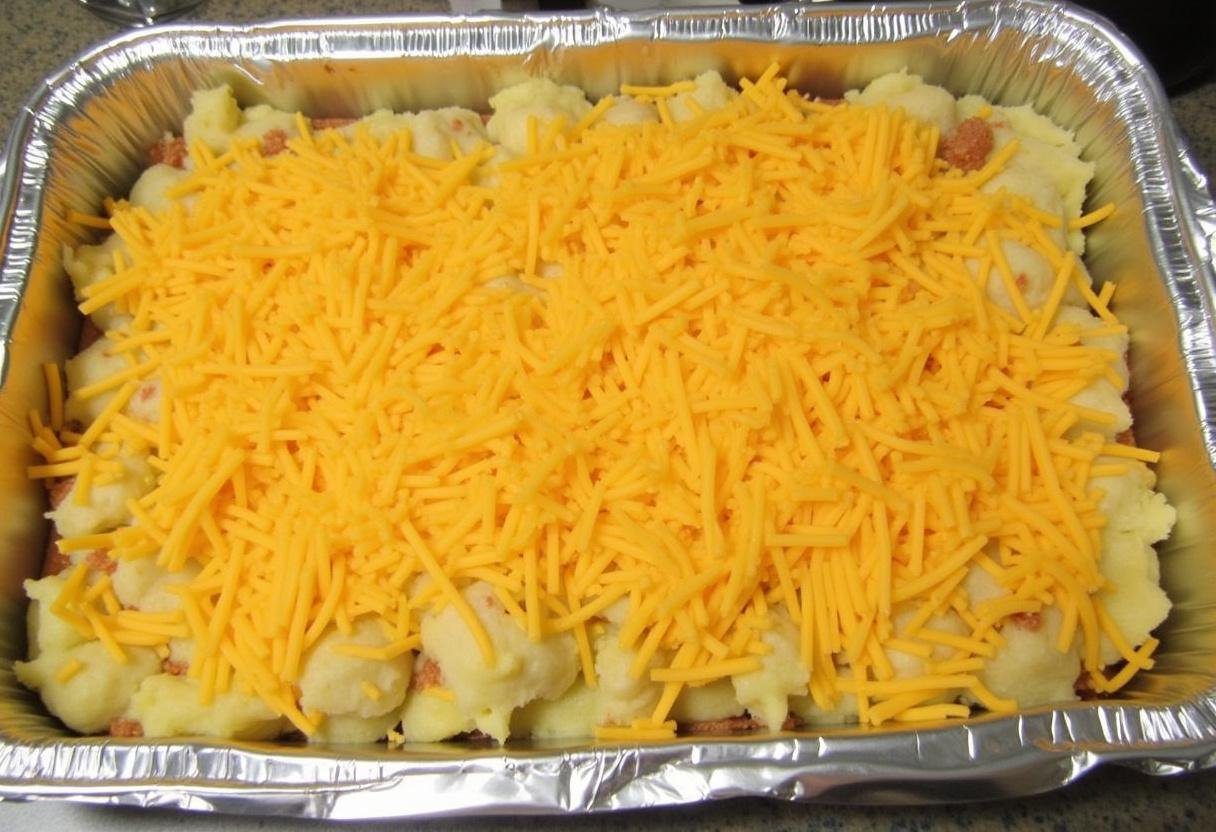 Transfert du mélange de patates douces et pommes de terre dans un plat allant au four beurré pour le gratin, ajout de fromage et de muscade.