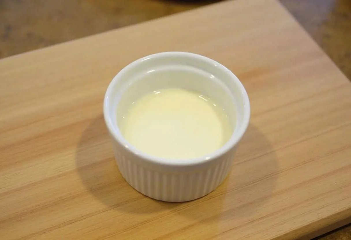 Ramekin with a layer of cream ready for Œufs Cocotte Crémeux preparation.