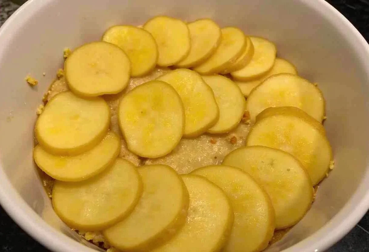 Préparation initiale pour Pommes Anna avec des pommes de terre tranchées et un plat beurré, recette de cuisine facile.