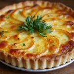 Quiche thon poireaux dorée prête à être servie, présentée sur une table en bois rustique avec des herbes fraîches.