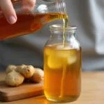 Sirop de gingembre maison dans une bouteille en verre, mettant en valeur sa couleur dorée et son arôme appétissant.