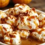 A close-up of a glass mug filled with rich, dark coffee topped with a generous swirl of marshmallow and a dusting of cinnamon, set against a cozy fall backdrop with pumpkins and autumn leaves. The syrup bottle sits nearby, showing a thick, caramel-colored liquid inside.