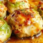A plate of golden-brown stuffed cabbage rolls arranged neatly, topped with a rich tomato sauce, garnished with fresh parsley. The rolls are tender with visible layers of cabbage and seasoned filling, served alongside a side of steamed vegetables.