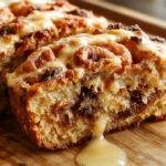 A freshly baked Cinnamon Roll Banana Bread loaf sliced to reveal a moist interior swirled with cinnamon and banana chunks, topped with a golden-brown cinnamon glaze, presented on a rustic wooden board with a sprinkle of cinnamon and banana slices around.