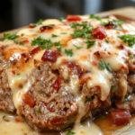A hearty meatloaf sliced open to reveal a moist, seasoned interior. The slices are arranged on a rustic plate, topped with a glossy tomato glaze and garnished with fresh herbs. The background features a cozy kitchen setting with a fork and knife placed beside the meatloaf.