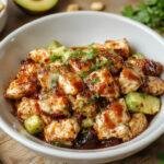 Close-up of a vibrant grilled chicken teriyaki bowl with fresh vegetables and rice, topped with sesame seeds