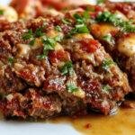 A rustic ceramic dish features a perfectly sliced homestyle meatloaf glazed with a shiny tomato-based sauce, revealing a moist, tender interior with visible bits of herbs and vegetables. The slices are arranged neatly on a wooden serving board, garnished with sprigs of fresh herbs, surrounded by a cozy kitchen setting with warm lighting and comforting elements.
