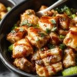 A vibrant bowl featuring sliced glazed teriyaki chicken arranged neatly over steamed white rice, topped with fresh green scallions and sesame seeds, with colorful vegetables on the side. The glossy chicken has a rich caramelized glaze, contrasting with the fluffy rice and crisp vegetables, all presented in a clean, modern bowl.