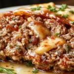 A centrally placed classic meatloaf glazed with a shiny tomato-based sauce, sliced to reveal a moist, tender interior with visible herbs and breadcrumbs, served on a rustic wooden platter with fresh herbs garnish.
